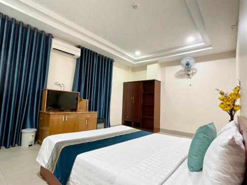 a bedroom with a bed and a tv and blue curtains at Hoa De Nhat Hotel- Sân Bay Tân Sơn Nhất in Ho Chi Minh City