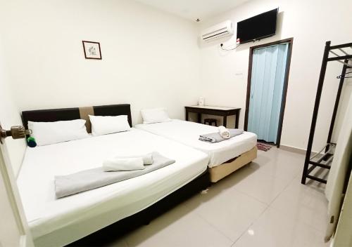 a white bedroom with a large bed with white sheets at MN Ferringhi Inn in Batu Ferringhi