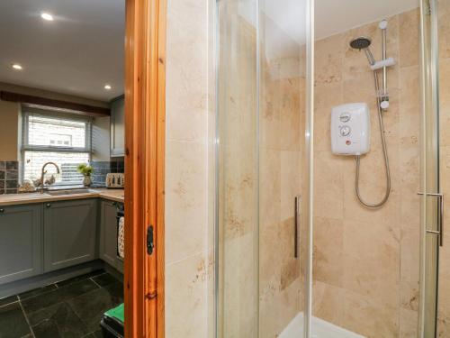 a bathroom with a shower with a glass door at Thimble Cottage in Ulverston