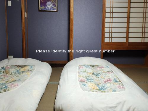 two beds sitting next to each other in a room at Narita Sando Guesthouse in Narita