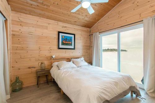 a bedroom with a bed in a wooden wall at **WATERFRONT**BEAUTIFUL MODERN TOBERMORY COTTAGE in Miller Lake