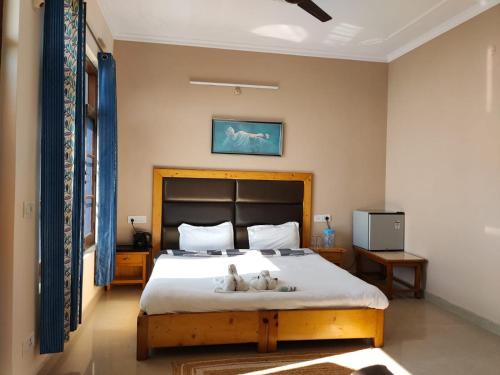 una camera da letto con un letto con due gatti sdraiati sopra di Yoga House a McLeod Ganj