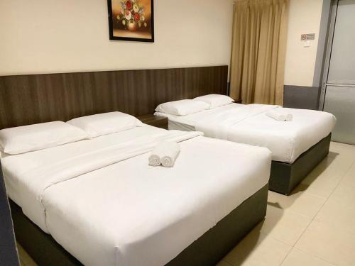 two beds in a hotel room with white sheets at Chemor Inn in Cemur