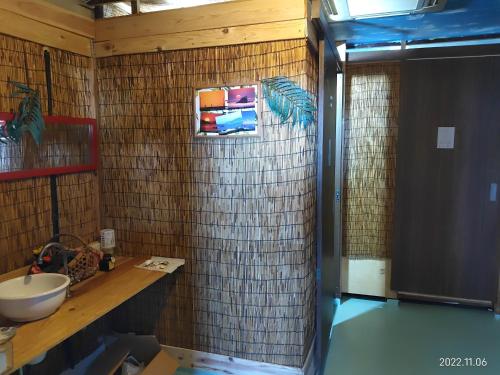 a bathroom with a sink and a tiled wall at イマジンウエストオーシャン（ImagineWestOcean） in Suo Oshima