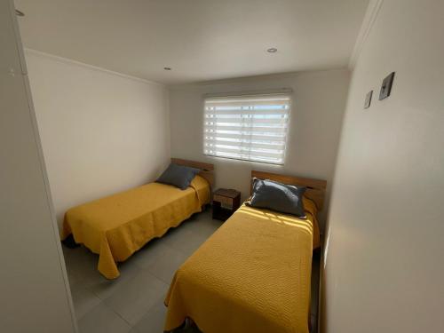 2 camas en una habitación pequeña con ventana en Casa condominio costa del Sol a 1.4 km de Bahía Inglesa, en Caldera