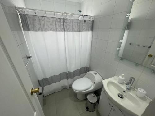 a white bathroom with a toilet and a sink at Casa condominio costa del Sol a 1.4 km de Bahía Inglesa in Caldera