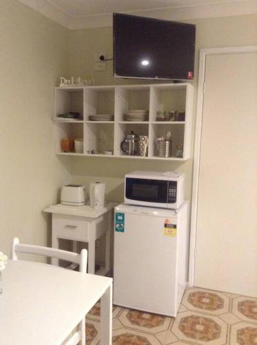 a kitchen with a small white refrigerator and a table at Seascape in Forster