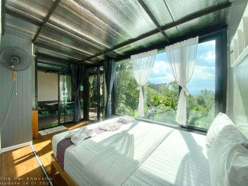 Bett in einem Zimmer mit einem großen Fenster in der Unterkunft The Owl Khaokho in Khao Kho