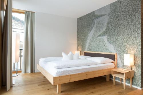 a bedroom with a large bed with white sheets at Steindl's Boutique Hotel in Vipiteno