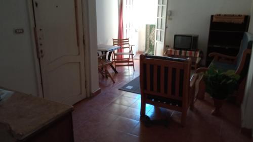 a living room with chairs and a table and a television at El Fardous Flowerللرجال فقط in Alexandria