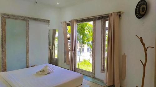 sypialnia z łóżkiem i dużym oknem w obiekcie Surga Tropical Suites w mieście Jimbaran
