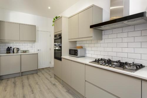 a kitchen with white cabinets and a stove top oven at Heyshott Manor - Luxury 5 bedroom house in Portsmouth in Portsmouth