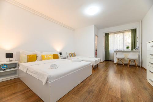a white bedroom with a large bed and a desk at JAD - Family Apartments & Studios in Braşov