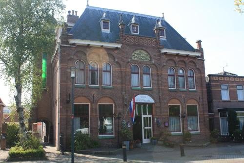 un grand bâtiment en briques rouges avec un toit noir dans l'établissement Hotel Saint Vincent, à Poeldijk