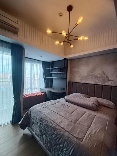 een slaapkamer met een groot bed en een kroonluchter bij Apartemen Taman Melati Yogya by The Cantigi in Kejayan