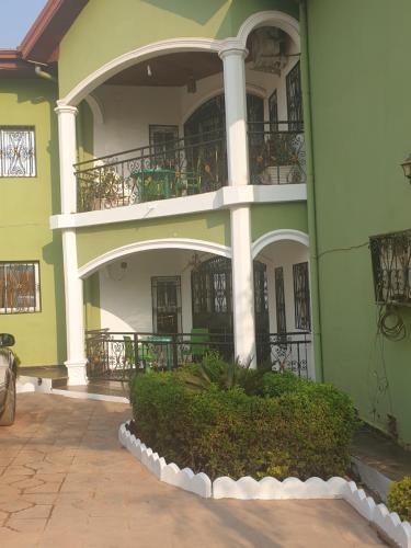 a green building with balconies and a courtyard at PN Meublés FULL OPTION Odza Dispose d'une voiture et un chauffeur gratuitement de l,aéroport aux appartements pour des réservations minimum de 7 jours in Yaoundé