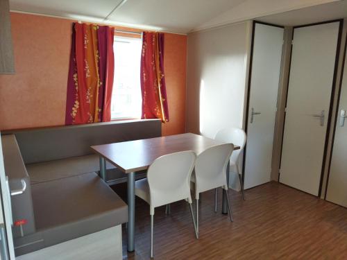 Cette petite chambre comprend une table et des chaises blanches. dans l'établissement mobil home 6 personnes, proche d'Europa Park et Rulantica, à Boofzheim