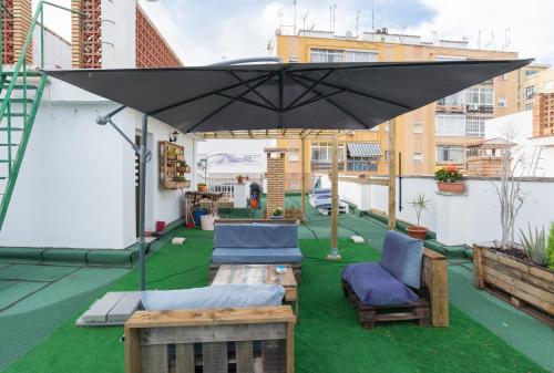 a patio with an umbrella and chairs on a roof at Rafaela Guest House in Málaga