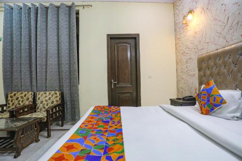 a bedroom with a bed and a chair and a door at FabHotel HM Palace in Noida