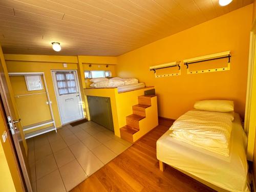 1 dormitorio con paredes amarillas, 1 cama y una escalera en An elegant studio apartment in Reykjavik - Great Location, en Reikiavik