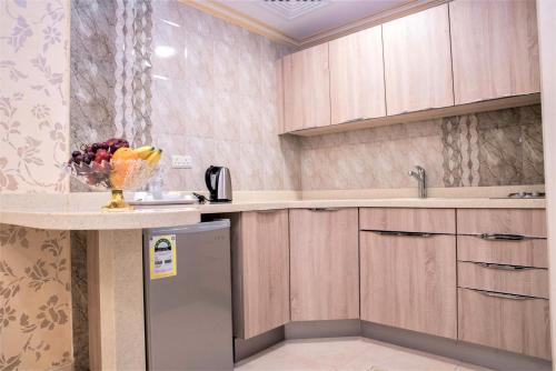 una cocina con armarios de madera y un bol de fruta en una barra en سارا للشقق الفندقية Sara Furnished Apartments en Al Khobar