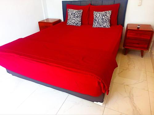 a red bed with red sheets and pillows in a bedroom at Loka Anyar Guest House in Kerobokan