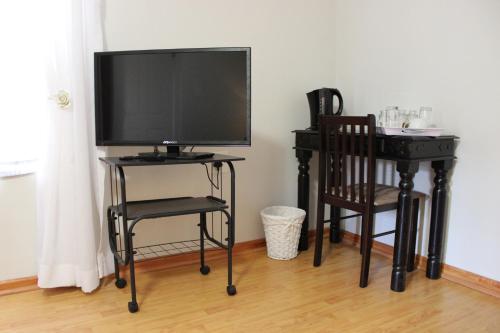 a television on a stand with two chairs and a desk at Blue Crane Guesthouse in Maseru