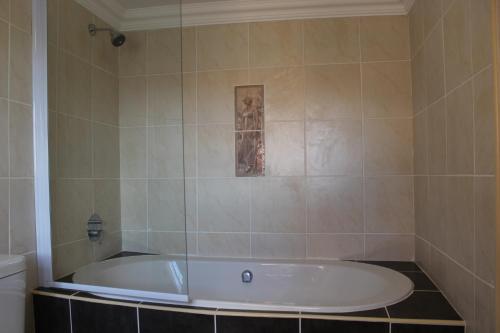 a bath tub in a bathroom with a tile wall at Blue Crane Guesthouse in Maseru