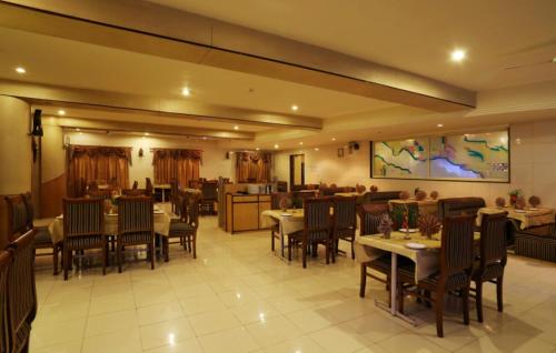 un comedor con mesas y sillas en un restaurante en Hotel Atithi, Aurangabad, en Aurangabad