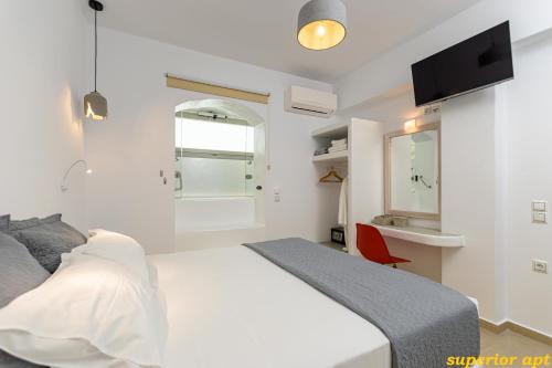 a bedroom with a white bed and a red chair at Aphrodite Luxury Apartments in Agios Prokopios