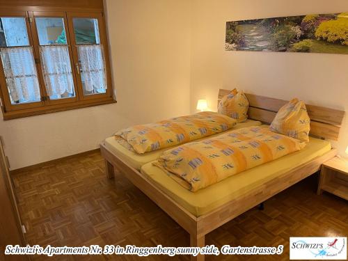 a bedroom with a bed with yellow comforter at Schwizi's Apartments in Ringgenberg
