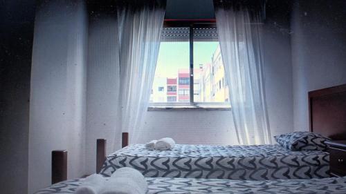 a bedroom with two beds and a window at GG Massamá Rooms in Queluz