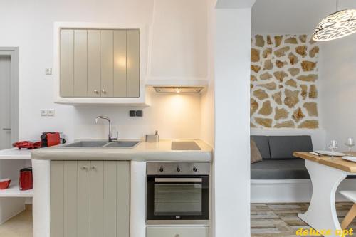 eine Küche mit weißen Schränken, einer Spüle und einer Couch in der Unterkunft Aphrodite Luxury Apartments in Agios Prokopios