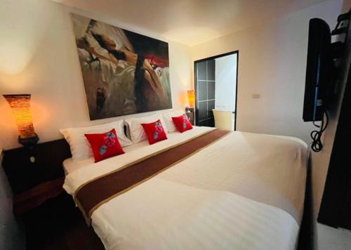 a bedroom with a large white bed with red pillows at Baipho Lifestyle in Patong Beach