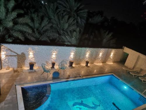 a swimming pool at night with chairs and lights at Yacob's MagicLand in Al Ḩamīdīyah