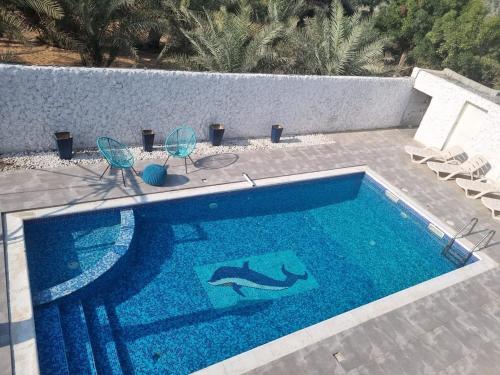 een zwembad met twee stoelen en een tafel en een zwembad bij Yacob's MagicLand in Al Ḩamīdīyah