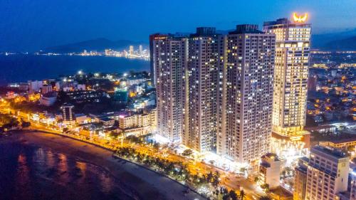 une ville éclairée la nuit avec de grands bâtiments dans l'établissement Oceanus Oasis Retreat Muong Thanh Vien Trieu, à Nha Trang
