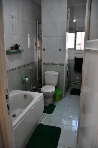 a bathroom with a toilet and a tub and a sink at Agouza NileView Apartment in Cairo