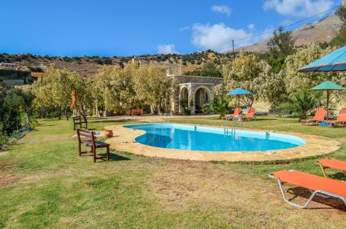 una piscina en un patio con sillas y sombrillas en Petra-Mare 2, en Triopetra