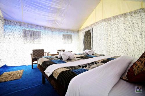 a bedroom with two beds in a room with a ceiling at Desert Oasis Camp in Hundar