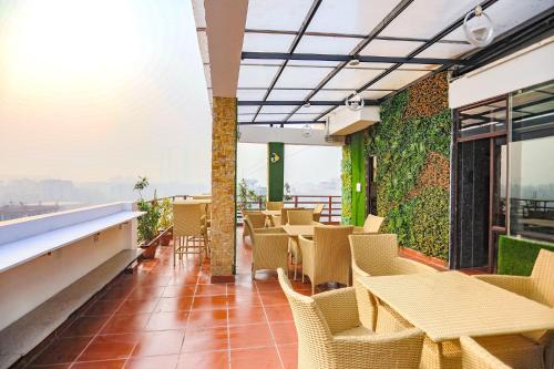 a restaurant with tables and chairs on a balcony at FabHotel The Horizon in Noida