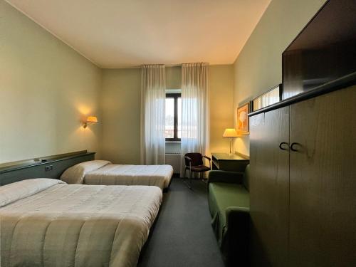 a hotel room with two beds and a desk at Hotel La Goletta in Binasco