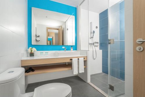 a bathroom with a toilet and a sink and a mirror at Holiday Inn Express Shunde Daliang by IHG in Shunde