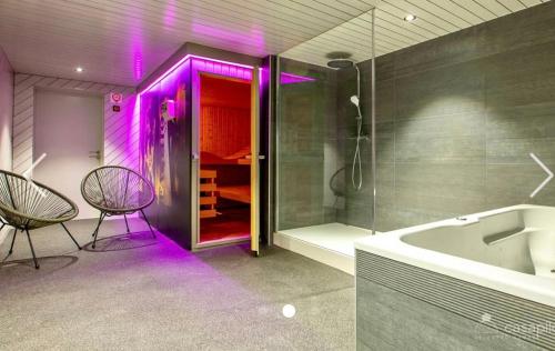 uma casa de banho com uma banheira e um chuveiro com luzes roxas em Côté Mont em Malmedy