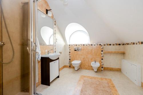 a bathroom with a toilet and a sink and two windows at Comfortable 4 bedroom villa outdoor wood-fired sauna Warsaw in Magdalenka