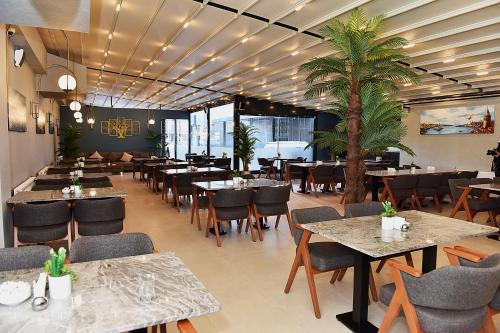 un restaurante con mesas, sillas y una palmera en Kerthill Hotel, en Estambul