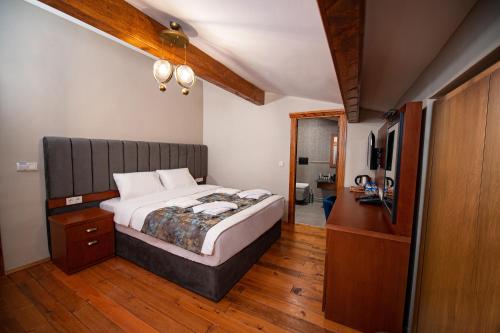 AHISKA PALAS OTEL في كارس: غرفة نوم بسرير وخزانة وتلفزيون