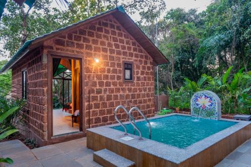 a brick building with a swimming pool in front of it at Nirvana Hill Resort in Curtorim