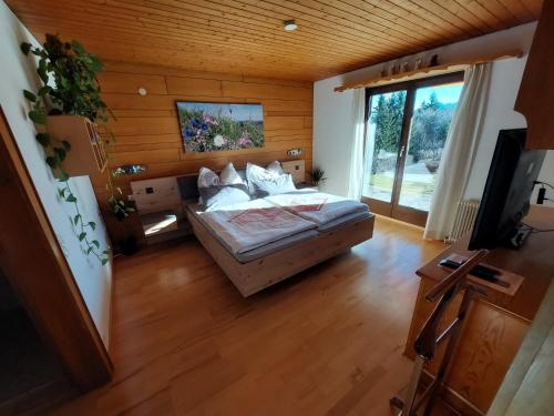1 dormitorio con cama y ventana grande en Ferienwohnung Tschengla mit eigener Sonnenterrasse - Wiese - Wlan - Netflix, en Bürserberg