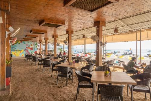 un comedor con mesas y sillas y la playa en Palolem Beach Resort, en Palolem